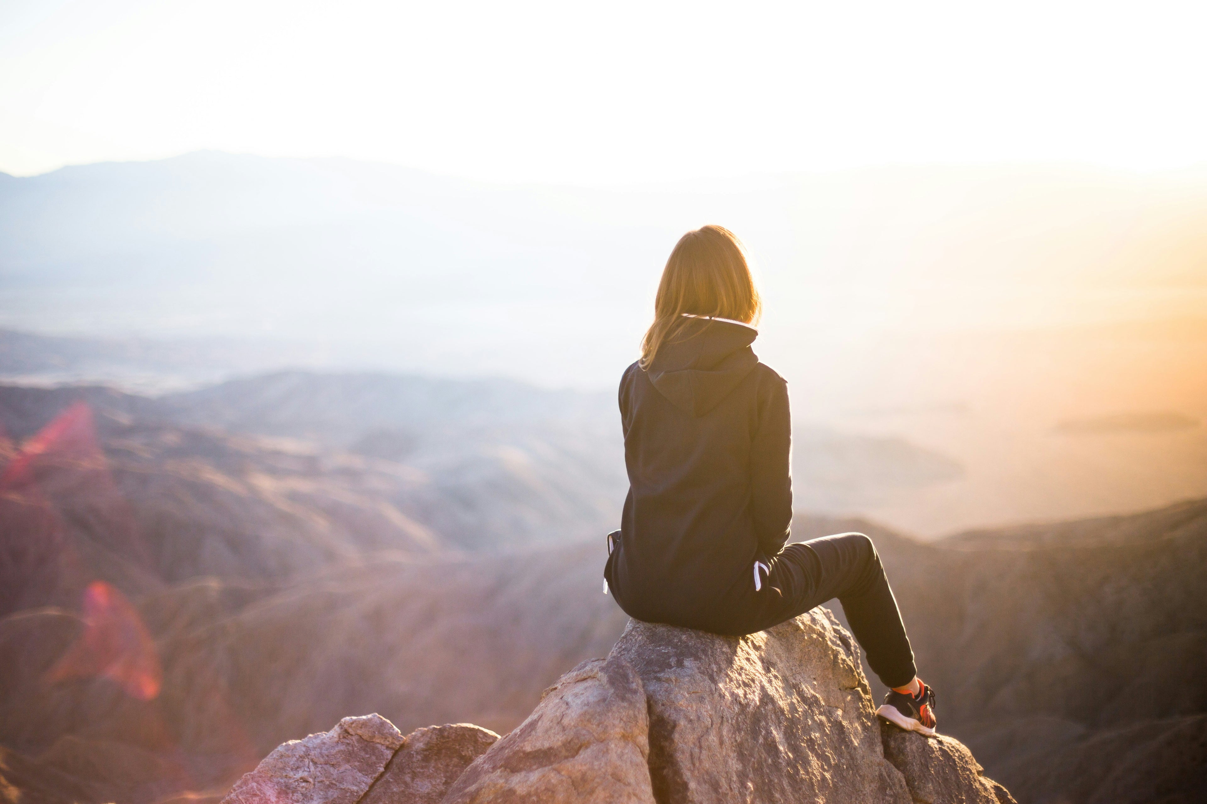 woman sitting on mountain peak - attribution: unsplash.com